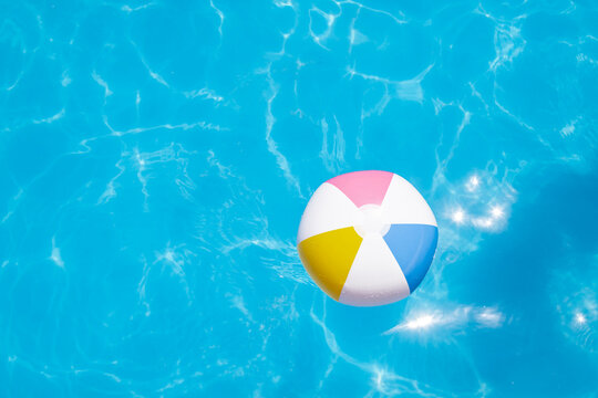 Colorful inflatable beach ball in a sunny pool