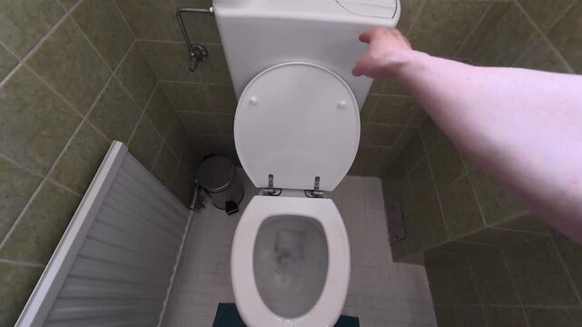 POV of hand flushing a toilet and lowering the toilet lid.
