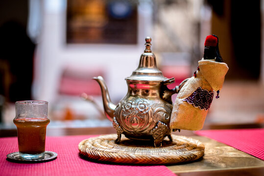 Traditional Moroccan teapot with glass on woven mat
