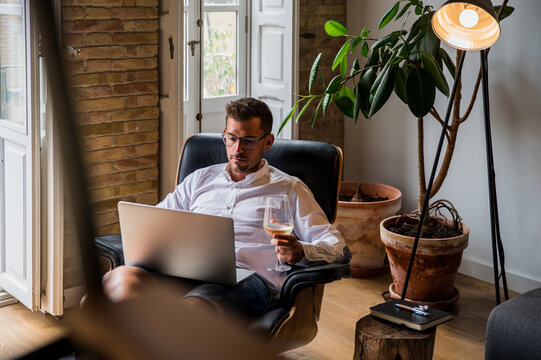 Businessman working in laptop and drinking wine
