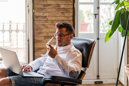 Businessman working in laptop and drinking wine