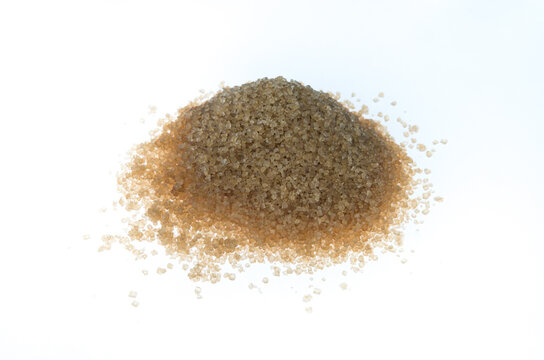 A pyramidal pile of brown cane sugar form the side, on white background