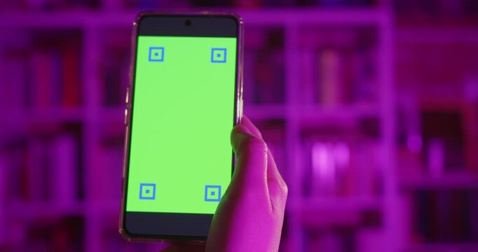A woman holding a smartphone at home in the night