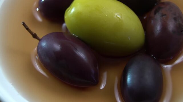 Assorted olives (Olea europaea) submerged in cloudy brine, lactic acid fermentation process, Food Science Background.