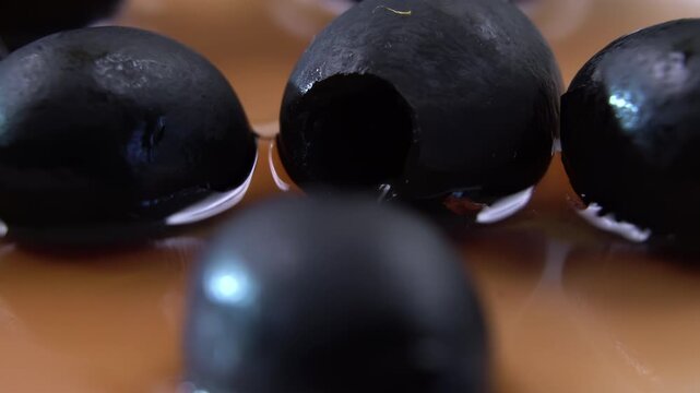 Pitted black Olives (Olea europaea) submerged in cloudy brine, liquid penetration into the mechanically pitted cavity, Food Science Background.