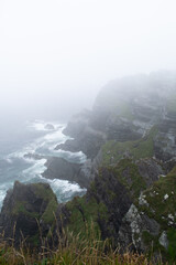 Naklejka premium Falaises du cercle de Kerry sous la brume irlandaise avec une mer agitée
