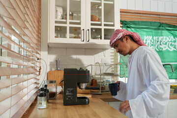 A Muslim man from the Middle East stands in his home kitchen, brewing coffee with an espresso machine for breakfast.  © supAVADEE BUTRADEE