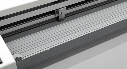 Obraz premium automated textile cutting machine precisely processing stacked light grey material illustrating industrial automation and modern manufacturing.