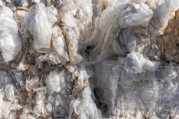 A detailed close-up of massive bales of crushed plastic wrap and industrial film, ready for...