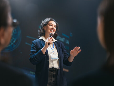 Confident Female Speaker Presenting at Business Seminar on Stage