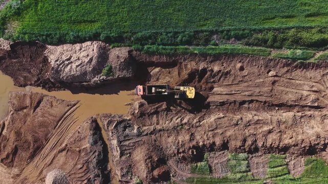 Orbital sobre la cantera: gr&uacute;a llenando el dumper mientras se revela el contorno completo