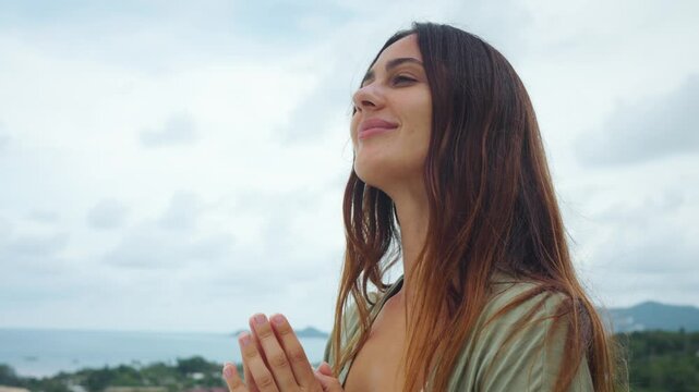 Mindfulness woman stands outdoors with hands together enjoying calm moment in nature. Mindfulness lifestyle shows inner peace balance gratitude scenic view and emotional wellbeing.