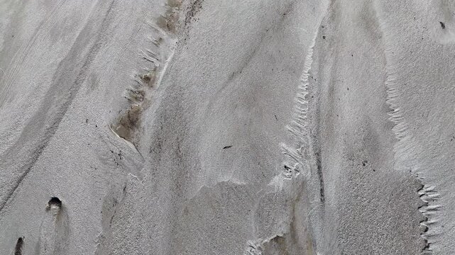 Water eroding sand creating miniature riverbeds