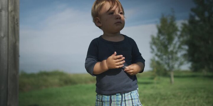 Toddler standing outside holding a pencil in nature