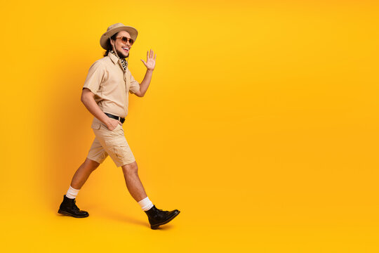 Man in safari outfit walks confidently against a bright yellow backdrop adventure travel and summer style for stock photography and lifestyle projects