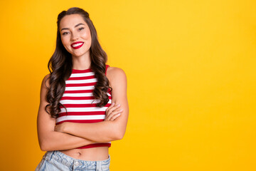 Bright smiling young woman with striped red top standing against yellow background for fashion...