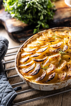 Golden-brown gratin potatoes, neatly arranged in a white ceramic bowl and garnished with fresh herbs. In Slovakia, however, this dish is known primarily at home as French potatoes