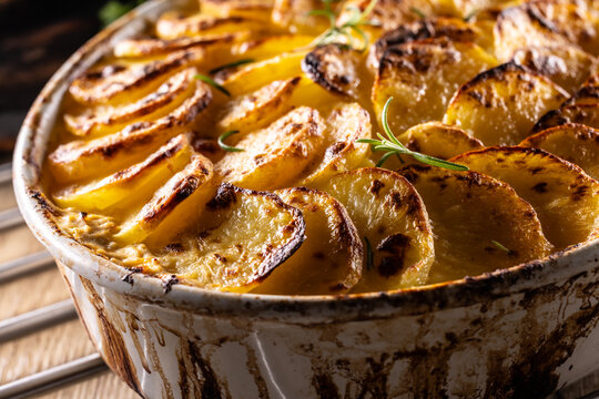 Golden-brown gratin potatoes, neatly arranged in a white ceramic bowl and garnished with fresh herbs. In Slovakia, however, this dish is known primarily at home as French potatoes