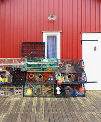Fototapeta premium Stacked lobster traps against red wooden fishing house in Smögen Sweden