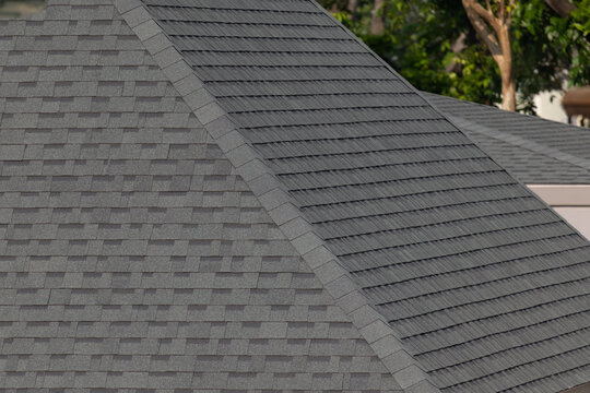 Dark gray shingles line a sloped roof with neat rows