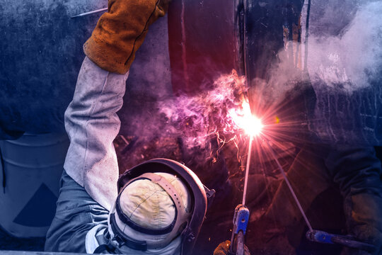 Worker with protective mask welding bore pile metal casing at a construction site
