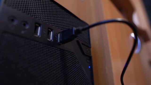 A USB cable and flash drive are connected to a computers USB port in an office, close-up view, technology