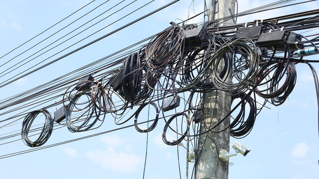 Tangle of cables and wires on the pole. Chaos of disorganized and tangled cables and wires on Thailand electrical poles in bottom view with selective focus.
