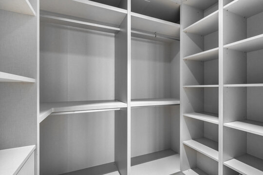 Empty modern closet with white shelves and hanging space. Minimalist design, organized storage area, suitable for home interiors.