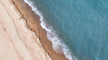 Fototapeta premium Tropical beach landscape from drone perspective showing turquoise sea and smooth sand coastline. Minimal natural background ideal for travel websites, resort promotions, and summer design projects.
