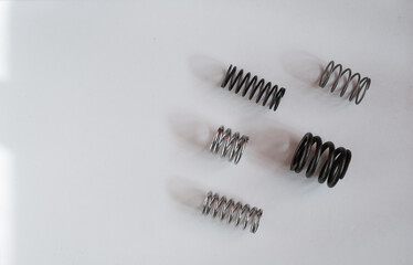 Fototapeta premium Set of metal coil springs on a white surface. Engineering, mechanics, industrial components. Top view. Copy space.