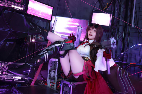 Girl in cosplay outfit sits on computer desk with sword
