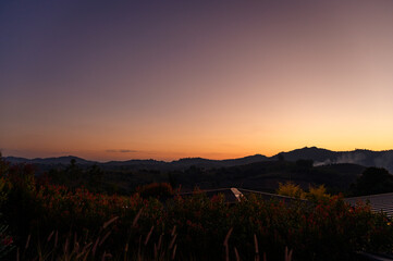 Beautiful mountain landscape during sunset with colorful gradient sky in shades of orange and purple. The calm scene captures the peaceful feeling of nature at dusk, ideal for travel, background use.