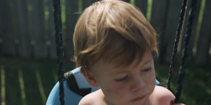 Young child sitting in a swing in the backyard