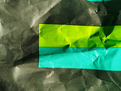 Textura de papel negro arrugado con un recuadro de color verde y azul