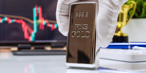 Hand Holding Gold Bar with Market Chart Investment Concept
