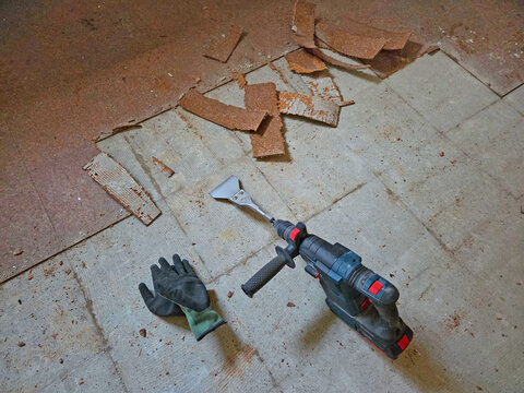 Rotary hammer with chisel for removing cork parquet flooring. Tool for old building renovation.