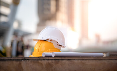 White and yellow hard safety helmet on concrete floor on city.