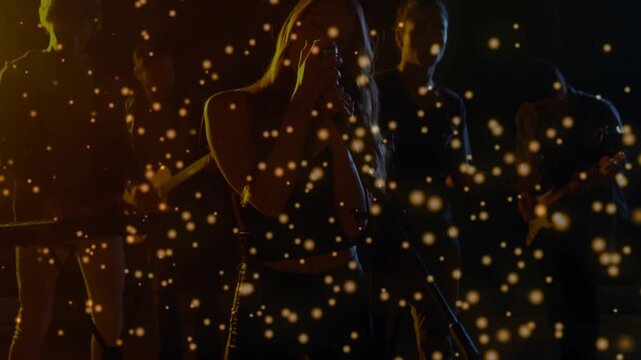 Vertical video: Shot rising to reveal female singer singing onstage band playing gold dust drifting