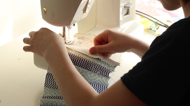 Teen boy sewing patchwork quilt with batting on sewing machine