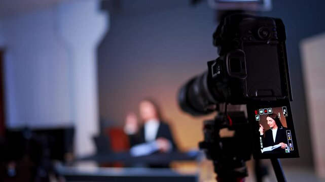 Beautiful brunette woman with long hair on the camera display. Photo and video equipment working in modern photo studio. Blurred backdrop.