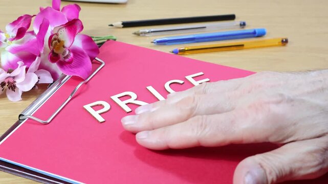 PRICE wooden sign with a man's hand sliding across a fuchsia sheet of paper, leaving copy space, sales concept.