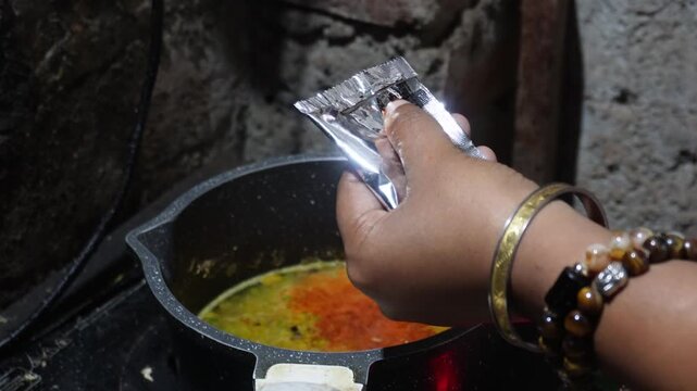 Persons enhance instant noodles by adding spices like chili flakes, garlic powder, soy sauce, or curry during cooking to boost flavor