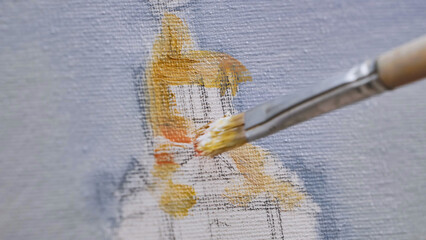 Artist painting on canvas with brush and yellow oil paint
