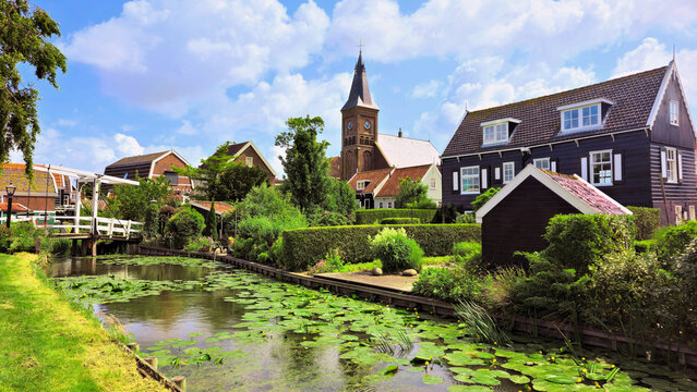 Traditional fishing village of Marken, Netherlands. Canal with bridge, traditional wooden houses and church