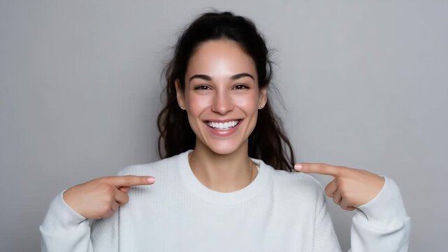smiling woman pointing at herself, self confidence concept, cheerful female portrait, positive emotion, white sweater, studio background, happy expression, self esteem, body language