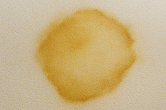 Unpleasant yellow urine patch soaked into mattress foam texture. close up showing damage and need for sanitation, highlighting common hygiene problem