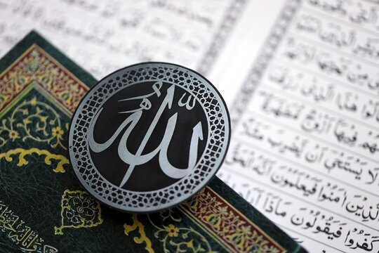 Sign with Islam inscription on Muslim holy book in mosque. Details of arabic calligraphy on sticker. Concept of Islam religion and praying in arabic countries