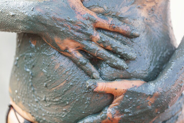 Obraz premium Hands rubbing mineral-rich mud on stomach as part of natural spa and detox therapy