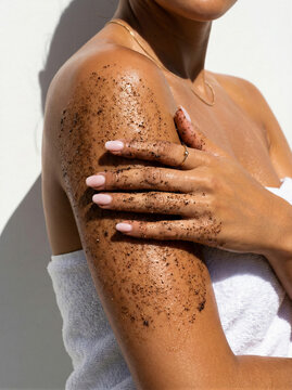 Woman applying body scrub on arm outdoors during a sunny day