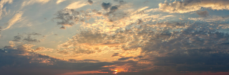 Obraz premium Dramatic sunset sky with jagged clouds glowing in blue and golden tones.